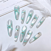 Mint Orbit silver shimmer square press-on nails styled with white feathers