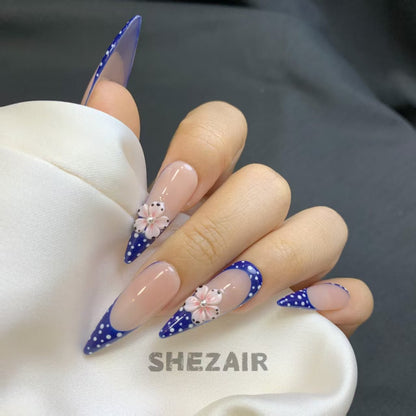 Hand model wearing royal blue polka dot floral stiletto press-on nails by Shezair